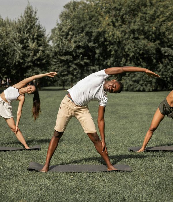 Diverse group of people smiling during a calm yoga session outdoors.