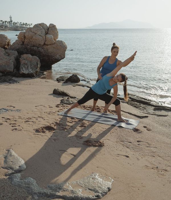 Woman greeting the sun in a peaceful yoga pose at dawn.
